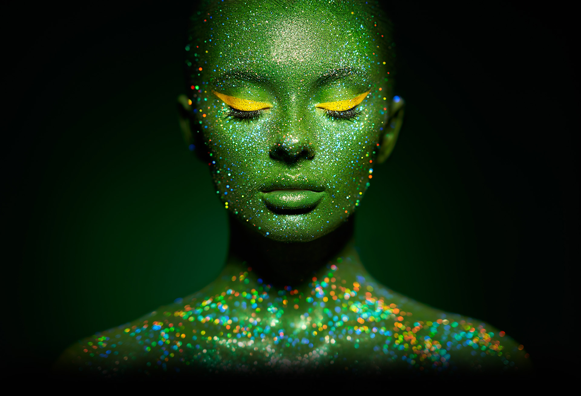 Headshot of female painted with green ultraviolet paint.